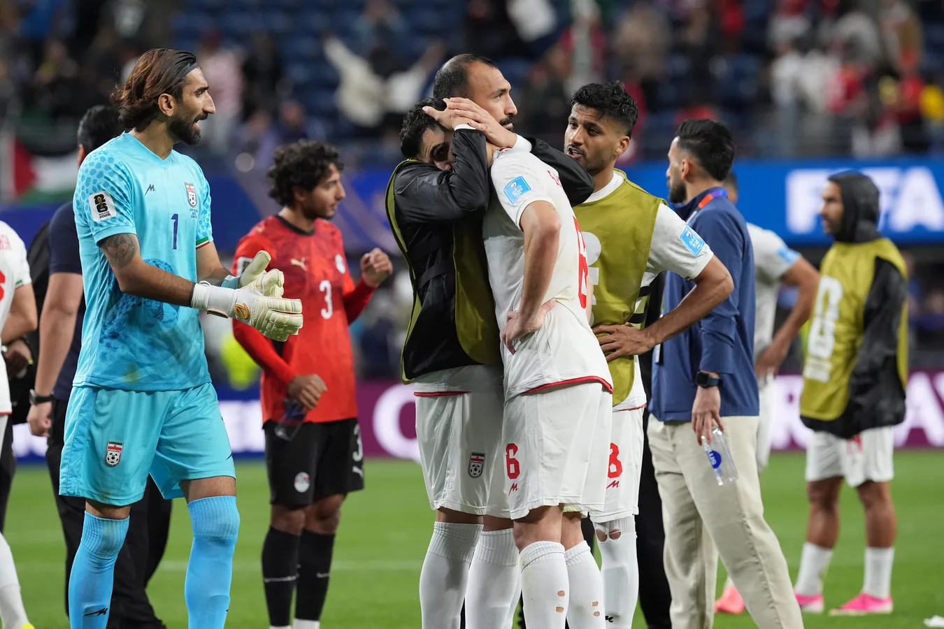 Bandeiras de Irán, Escocia e Túnez lado a lado no gramado de um estádio
