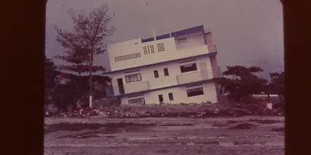 Retrato de Raúl Osuna con cámara fotográfica junto a planos de ingeniería tras el terremoto de 1967
